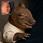 A close-up photo of a smiling newborn baby snuggled against a dark fabric, with soft lighting highlighting the peaceful expression and tiny features, set against a cozy background with a colorful knitted blanket and a red quilt.
