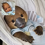 A cheerful baby lounges like a tiny VIP in a cozy nest of blankets, giving the camera a charming little smirk while a pacifier stands by as the official backstage manager.