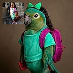 A cheerful young girl stands confidently near a chain-link gate, dressed in a mint green outfit with a bright green bow in her curly hair and a pink backpack. She's holding a phone case and wearing colorful sandals, basking in the warm sunlight that creates playful shadows on her face.