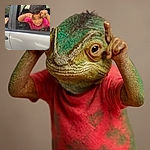 A playful young boy leans out of a car window, making funny hand gestures above his eyes like little horns, with a mischievous smile and bright eyes, wearing a pink shirt inside a silver car parked near a textured wall.