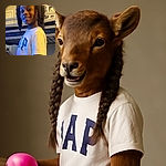 A smiling child with two big puffs of hair stands indoors near a bunk bed, holding a glowing purple object that casts a fun light on their hands, while the background shows a cozy room with a door and a backpack hanging.