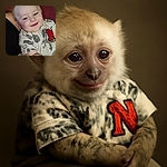 A smiling toddler with bright blue eyes lounges comfortably, wearing a playful shirt with a big red 'N' patch, nestled against a cozy reddish couch. The warmth of the moment shines through despite the casual snap.