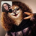 A cheerful young person with curly hair and glasses flashes a peace sign while smiling warmly at the camera against a plain wall background.