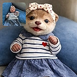 A cheerful baby wearing a cute striped dress and a heart-patterned headband lounges comfortably on a blue cushion, flashing a joyful smile that could melt any heart.