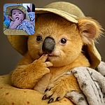 A chubby baby wearing a floppy yellow sunhat is caught mid-teething with fingers in mouth, wrapped snugly in a soft, spotted blanket, surrounded by colorful baby gear in a cozy indoor setting.
