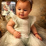 A chubby-cheeked baby sitting comfortably on a soft couch, wearing a cute light-colored outfit and quirky round sunglasses perched on the head, looking down with a sweet smile as if pondering the mysteries of the universe.