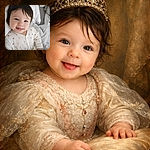 A cheeky, giggling baby in a polka-dot onesie lies snug on a bed, tongue playfully peeking out, tousled hair and sparkling eyes stealing the show — a cozy, soft-blanket portrait that screams 'cute mischief.'