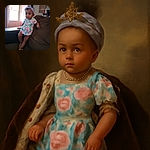 A toddler in a floral dress and sandals poses carefully on a brown couch, with a purple headband holding up her curly hair. The background shows a red door and a softly lit window, along with a cozy home setting.