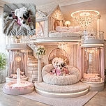 A fluffy white and black puppy wearing a pink and plaid outfit lounges adorably on a quilted beige couch, chewing on a treat with wide, curious eyes.