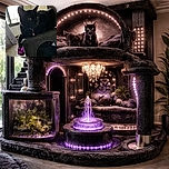 A sleek black cat with bright yellow eyes lounges on a textured cat tree, one paw dangling casually. The soft natural light from a nearby window highlights the cat's shiny fur and curious expression, while the room's details blur softly in the background.