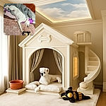 A white dog with light spots is stretched out comfortably on a blanket and carpet, holding a plush toy with its paw, surrounded by cozy bedding and wooden panel walls.