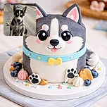 An adorable husky puppy sits attentively on a wooden floor, looking straight at the camera with curious eyes. Toys and home furnishings are visible in the background, giving a cozy indoor vibe.