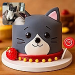 A curious gray and white kitten sits comfortably on a soft blanket, looking straight at the camera with big, bright eyes. The cozy indoor setting includes a door with glass panes and a TV in the background, creating a warm and homely vibe.