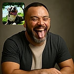 A happy, panting dog lies on the grass in the sunshine, basking in the warm light with a big smile and tongue out, framed by leafy green trees and a wire fence in the background.