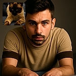 A close-up photo of a Siamese cat lying down with its paws stretched forward, its dark face contrasted against a softly blurred background, giving it a mysterious and regal vibe.