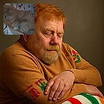 A blurry and dimly lit photo of a ginger cat curled up on a colorful patterned blanket, looking like it's ready for a nap but the camera forgot to focus.
