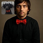 A charming black dog sporting a bright orange bow tie sits attentively on a tiled floor in front of a washing machine, looking like it's ready for a fancy occasion or maybe just a spin cycle of cuteness.