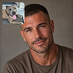 A big, happy dog lounges across the doorstep with its tongue hanging out like it has just delivered a very important slobbery speech. The textured doormat, open doorway, tiled floor, and weathered wall create a cozy home-entrance setting.