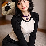 A tuxedo cat sits on a rug giving an earnest, wide-eyed stare as if it just practiced its most convincing 'feed me' look; hardwood floor, a dresser and a little towel peek out in the background while the cat's collar tag catches the eye.