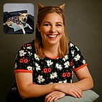 A happy dog lounges on a black leather couch, wearing a festive Halloween-themed shirt covered in ghosts and the word 'BOO'. The dog rests comfortably on a gray cushion, looking directly at the camera with a big, joyful smile, creating a cozy and cheerful atmosphere.