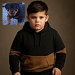 A close-up photo of an adorable Rottweiler puppy walking on a gravel surface, looking straight at the camera with a curious and slightly serious expression. The background is blurred, focusing attention on the puppy's fluffy fur and cute paws.