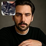 A close-up portrait of a black and white tuxedo cat with striking green eyes and white whiskers, resting comfortably on a soft surface with a paw prominently in the foreground.