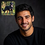 A handsome black-and-tan dog stands proudly in the sunshine, flashing a huge pink tongue like it just won an award for Most Dramatic Panting. The leafy outdoor background provides a warm, softly blurred stage for this four-legged superstar.