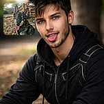 A striking dog with mesmerizing icy blue eyes sits obediently outdoors, tongue out in a happy pant, wearing a black harness. The sun filters through the green leaves above, casting a warm glow on the autumnal ground covered with fallen leaves. The background features a tree trunk and some rustic wooden pallets, adding a touch of countryside charm.