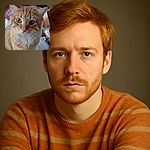 A close-up shot of an orange tabby cat with green eyes, slightly out of focus, sitting amidst a cluttered table with various household items like bananas, boxes, and a packet labeled 'Bath Bombs'.
