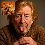 A fluffy, happy dog with a shaggy coat and tongue playfully sticking out, resting on a cozy blue blanket with a warm wooden background.