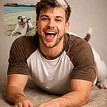 A cheerful bulldog lying on the sandy beach with its tongue out, looking very happy and a bit sandy, with a calm river and green trees in the background under a cloudy sky. The phrase 'Coup de projecteur' is overlaid at the bottom in large white text.