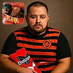 A regal Rottweiler lounges comfortably on a red leather couch, sporting a festive orange and black striped sweater with a cheerful pumpkin emblem. The dog rests its paw on a bright red 'Dogzilla' toy, looking calm and content in this cozy autumnal scene.