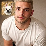A curious French Bulldog sits on a rustic wooden floor, looking up with big, expressive ears and a slightly wrinkled face, as if waiting for a treat or some attention.