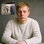 A sleepy Labrador stretches out on a wooden floor next to a gray couch, with a TV and a decorative vase in the background, looking like it's contemplating the mysteries of the universe or just waiting for a treat.
