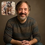 A happy dog sitting on a wooden bridge covered with autumn leaves, looking straight at the camera with a joyful expression and tongue slightly out, surrounded by a softly blurred natural background.