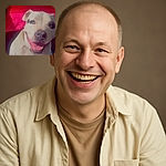 A happy dog with a light coat and a striking patch around one eye smiles widely in front of a bright red background, with tiny star-like sparkles adding a magical touch to the cozy indoor scene.