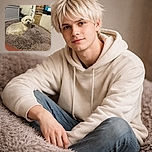 A fluffy white dog lounging on a plush, shaggy blanket in a cozy indoor setting. The photo is slightly out of focus, giving it a soft, dreamy vibe, but the dog's calm expression shines through the blur. The background shows a mix of brick and furniture, adding a homey atmosphere.