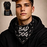 A serious-faced German Shepherd puppy wearing a cheeky 'BAD DOG' bandana, with its ears adorably folded back, staring intently against a plain background, making mischief look stylish.