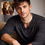 A close-up of a tabby cat lounging comfortably, its eyes wide and alert as if plotting world domination or just waiting for dinner. The background is softly blurred, highlighting the cat's striped fur and white chest patch.