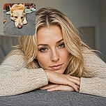 A sleepy cream-colored dog is sprawled across the bed with its enormous pink-and-black nose pressed toward the camera, looking like it has just completed a very serious nap. Behind it, patterned pillows and wooden cabinets create the cozy headquarters of maximum relaxation.