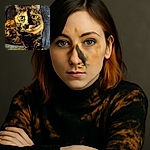 A tortoiseshell cat lounges comfortably, its strikingly patterned fur and big, curious eyes stealing the spotlight against a soft, textured background.