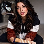 A big, fluffy Bernese mountain dog lounges on a tiled floor with one paw hugging a woven toy and its tongue flopping out like it just told a very good joke. The dog's soulful eyes and white chest make it look both regal and ridiculous — equal parts noble giant and goofball.