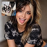 A playful little dog with one blue eye and one brown eye looks up eagerly with its tongue out, sitting on a beige mat next to a cozy dog bed and a black socked foot labeled 'DRI-FIT'.