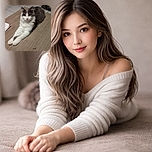 A fluffy white and gray cat lounges elegantly on a wooden floor, stretching its front legs forward with a calm and curious gaze directly at the camera. The background shows tiled flooring and some household items, creating a cozy indoor setting.