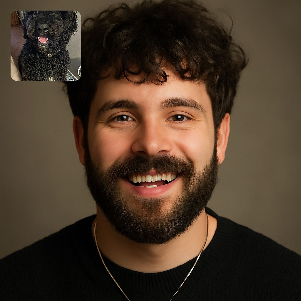A fluffy black curly-haired dog with a happy expression and tongue out, sitting indoors on a rug with some household items in the background.