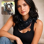 A sleek black dog lounges on a sunlit patio, sporting a stylish bandana and a shiny tag, looking at the camera with soulful eyes that say 'treats, please!' The background is softly blurred with greenery and a wooden fence, making this canine the star of the show.