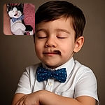 A charming black and white kitten snoozes peacefully, sporting a cute blue polka-dot bow tie, nestled comfortably against a person's arm and a soft pink fabric background.