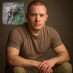 A curious dog with a serious expression lounges on a patch of dirt surrounded by scattered leaves and green plants, as if contemplating the mysteries of the backyard jungle.