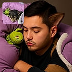 A cozy pup is snoozing contentedly in a soft pink bed, cuddling a green plush toy, while another dog is partially visible in the foreground, making it a heartwarming snapshot of pet comfort.