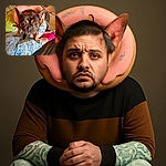 A curious French Bulldog wearing a pink donut-shaped collar stands on a person's lap clad in playful fish-patterned pajamas and bright pink socks, set in a cozy, slightly cluttered indoor space.
